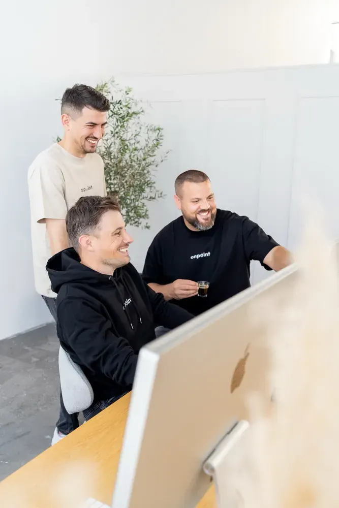 Drei Teammitglieder arbeiten gemeinsam an einem Bildschirm